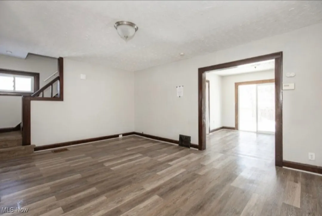 Empty room with visible vents, baseboards, stairway, wood finished floors, and a textured ceiling