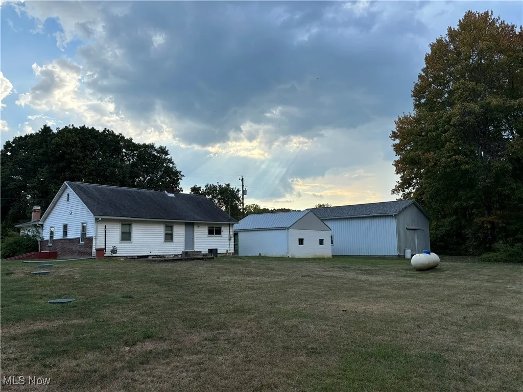 View of front of home featuring a front lawn and an outbuilding