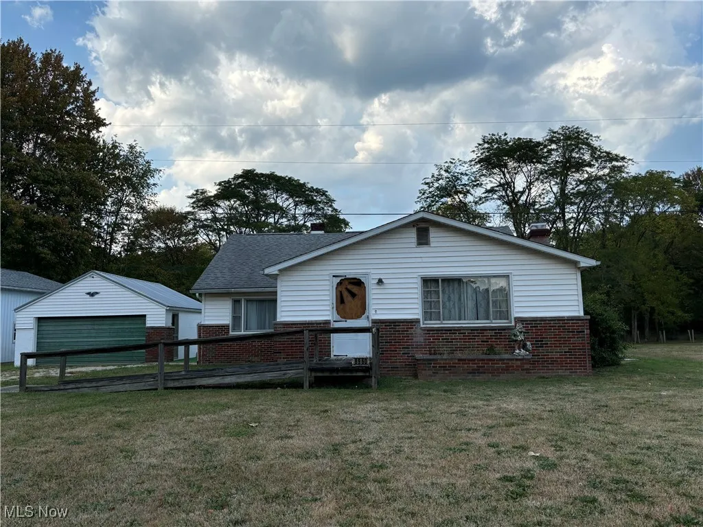 Bungalow-style house with brick siding, a garage, a front yard, and an outdoor structure