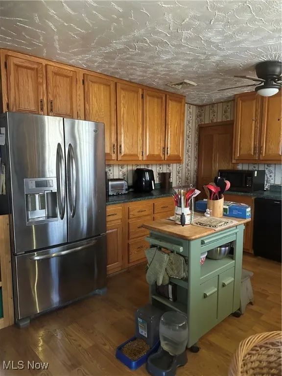 Kitchen with brown cabinetry, wood finished floors, dishwashing machine, and fridge