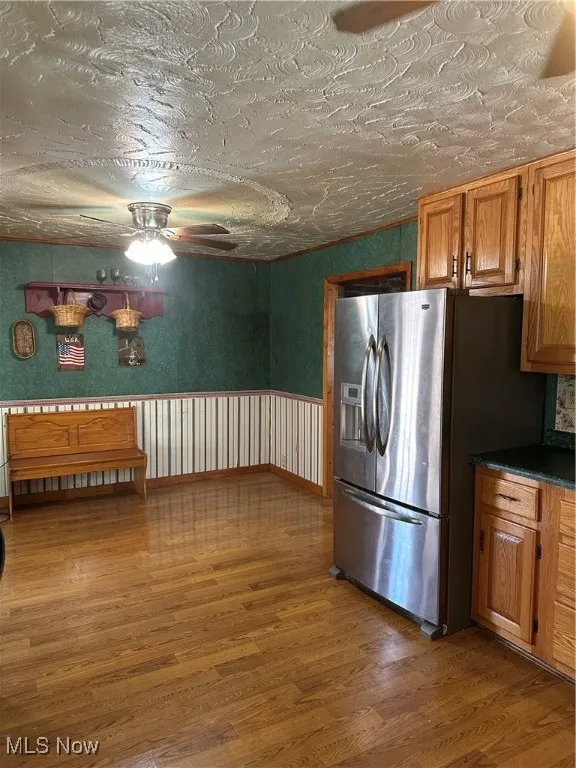 Kitchen with fridge, light wood finished floors, a ceiling fan, Amish Built Oak cabinetry, and dark countertops