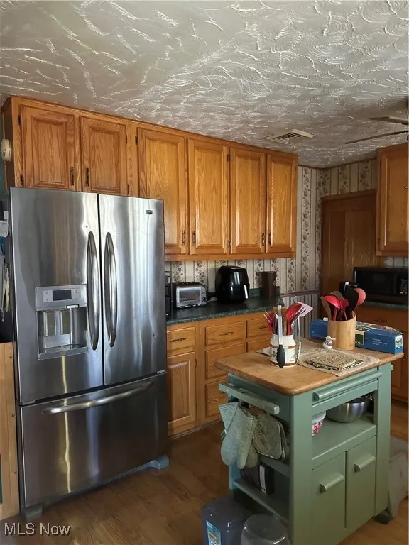 Kitchen featuring refrigerator, wood finished floors, brown cabinets, open shelves, and wallpapered walls