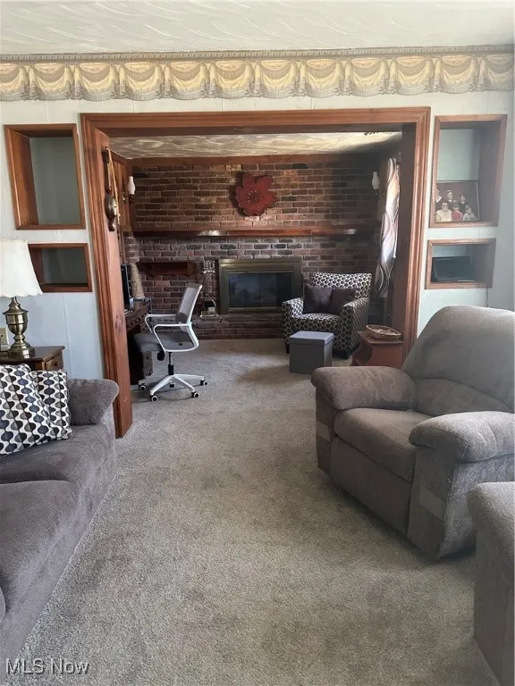 Living area featuring brick wall, carpet, and a brick fireplace