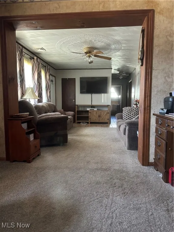 Living room featuring a ceiling fan, carpet flooring, and visible vents