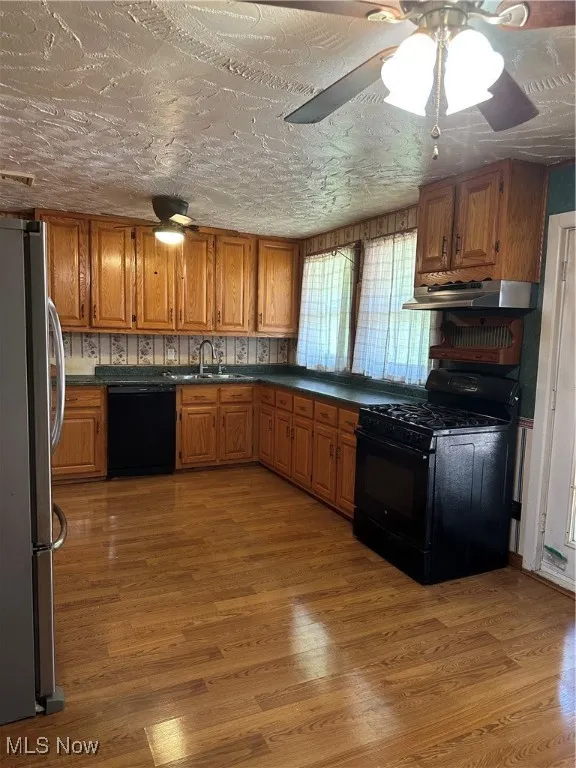 Kitchen featuring Amish made Oak Cabinets,  dishwashing machine, refrigerator, stove, ventilation hood, and a sink