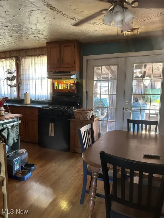 Kitchen with light wood finished floors, brown cabinetry, range, and french doors