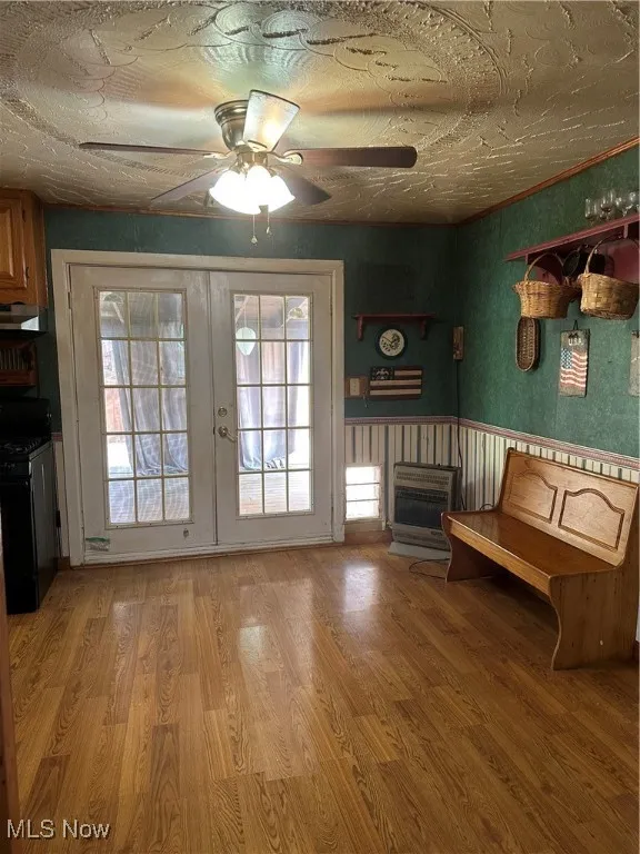 Entryway featuring heating unit, french doors, light wood-style floors, and a ceiling fan leading to covered porch and deck