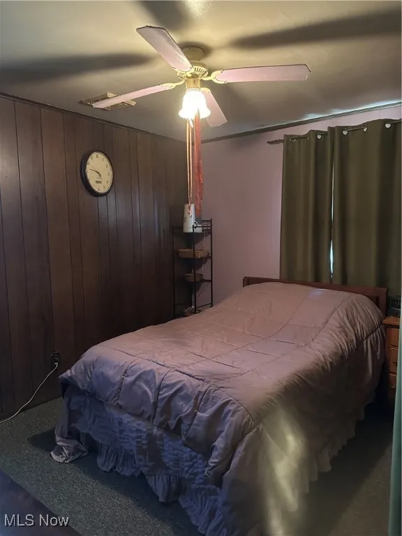 Bedroom with wood walls and ceiling fan