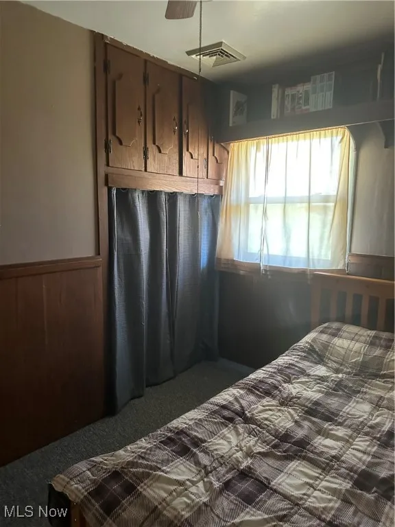 Bedroom featuring a wainscoted wall and visible vents