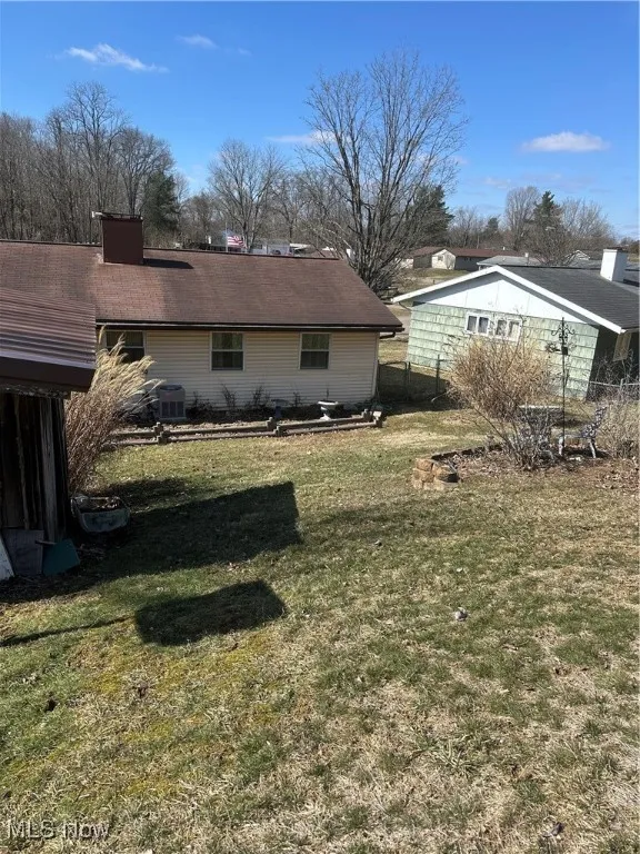 View of side of home featuring cooling unit and a yard