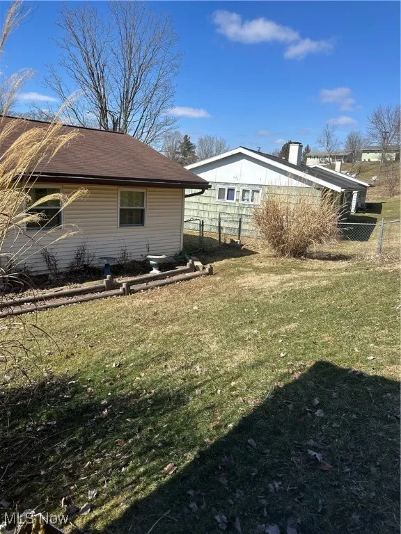 View of side of home featuring a lawn and fence