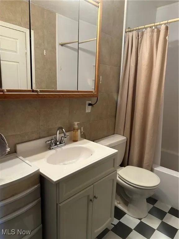 Full bath featuring toilet, tile patterned floors, vanity, tile walls, and decorative backsplash