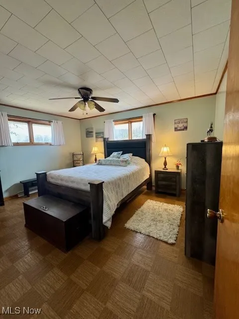 Bedroom featuring baseboards, multiple windows, ceiling fan, and crown molding