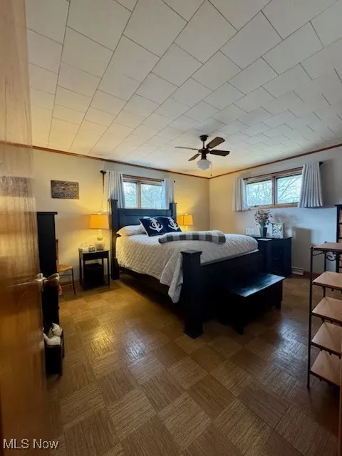Bedroom with multiple windows, a ceiling fan, and ornamental molding