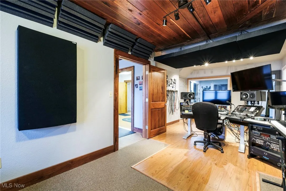 Office space with track lighting, wood ceiling, light wood-style floors, and baseboards