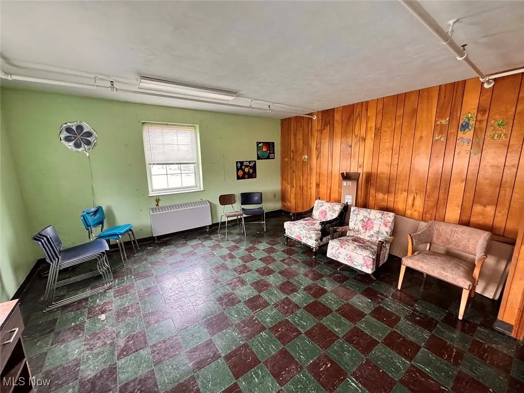 Unfurnished room with tile patterned floors, wooden walls, and radiator