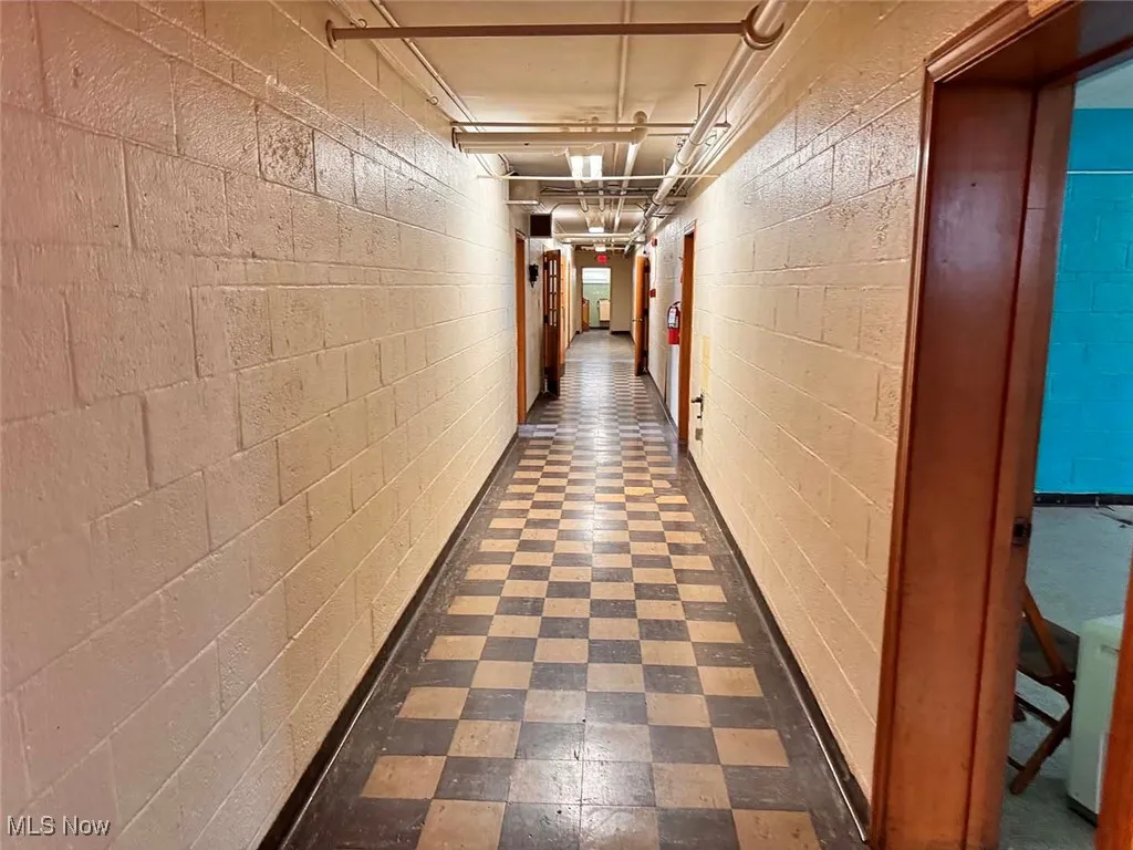 Corridor featuring concrete block wall and dark floors