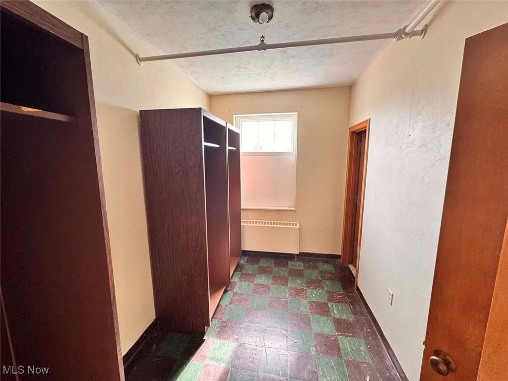 Hall with radiator heating unit, dark floors, baseboards, and a textured ceiling