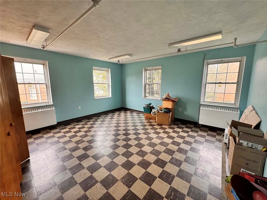 Spare room with radiator, baseboards, attic access, a textured ceiling, and tile patterned floors