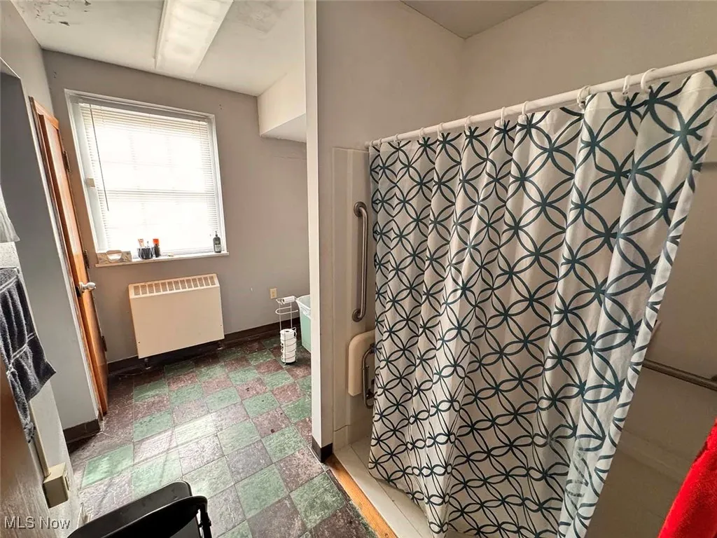 Bathroom featuring tile patterned floors, radiator, baseboards, and a shower with curtain