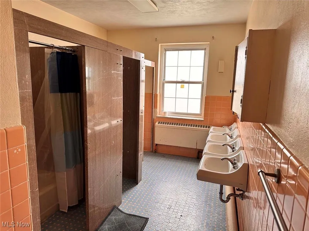 Bathroom featuring a shower with shower curtain, radiator, and a textured ceiling