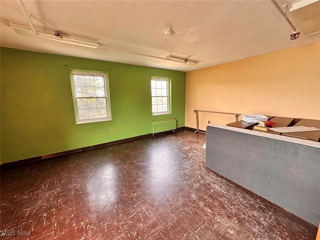 Empty room with tile patterned floors, radiator, and baseboards