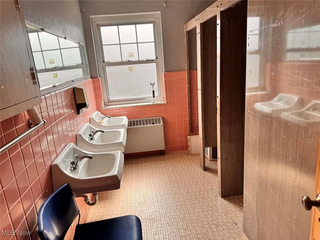 Bathroom with a sink, radiator, and tile walls