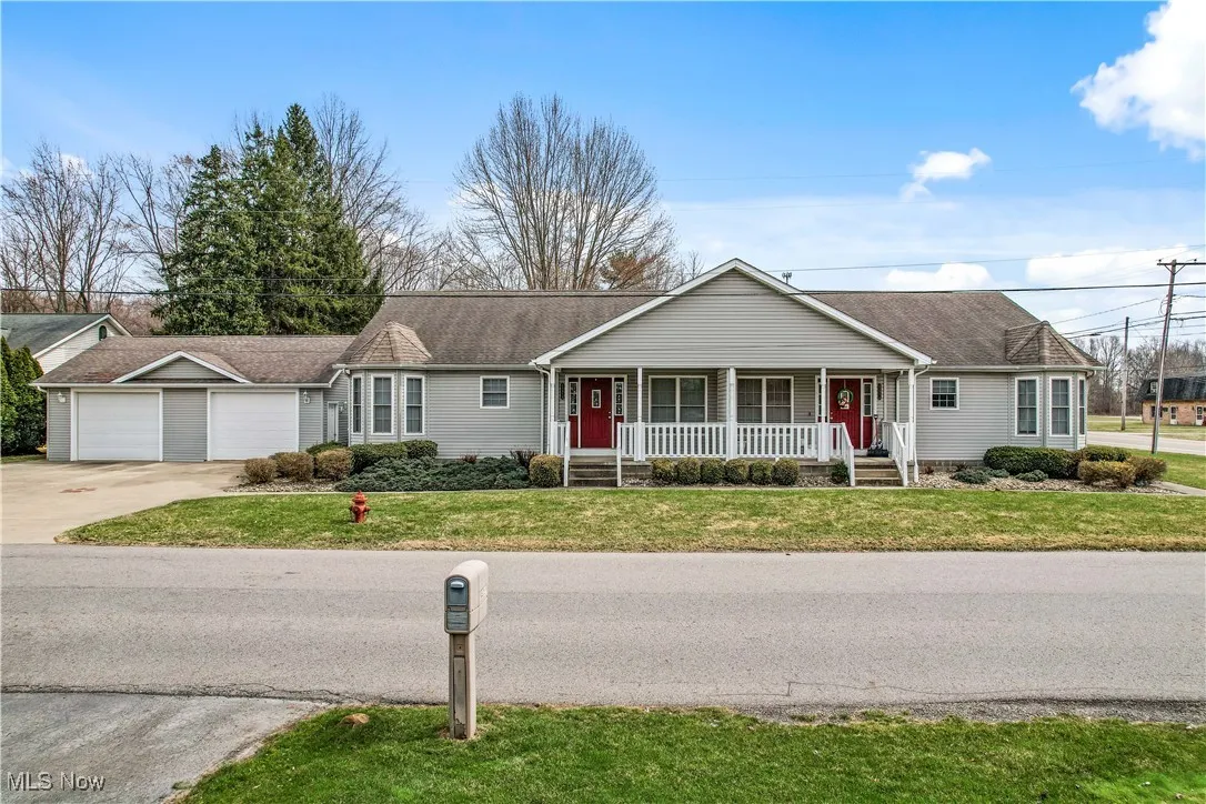 Ranch-style house featuring roof with shingles, concrete driveway, a garage, a front lawn, and a porch