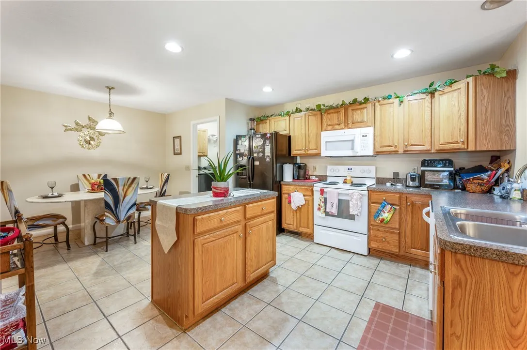 Kitchen featuring a center island, white appliances, a sink, and light tile patterned floors