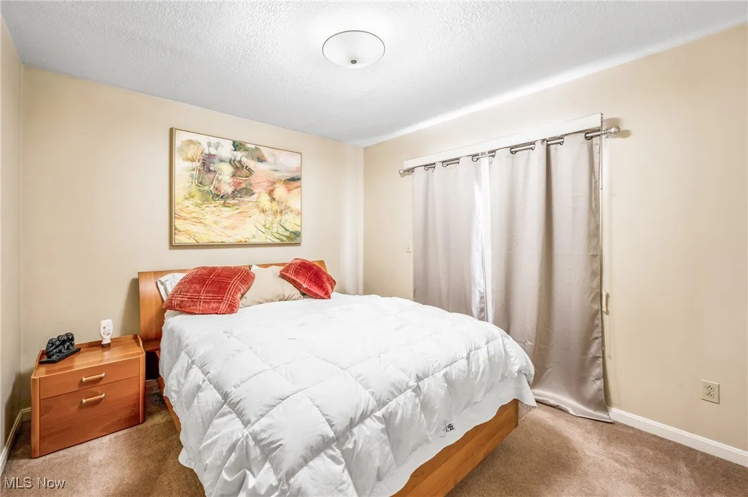 Bedroom with baseboards, carpet flooring, and a textured ceiling