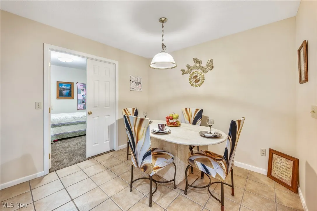 Dining space with light tile patterned flooring and baseboards