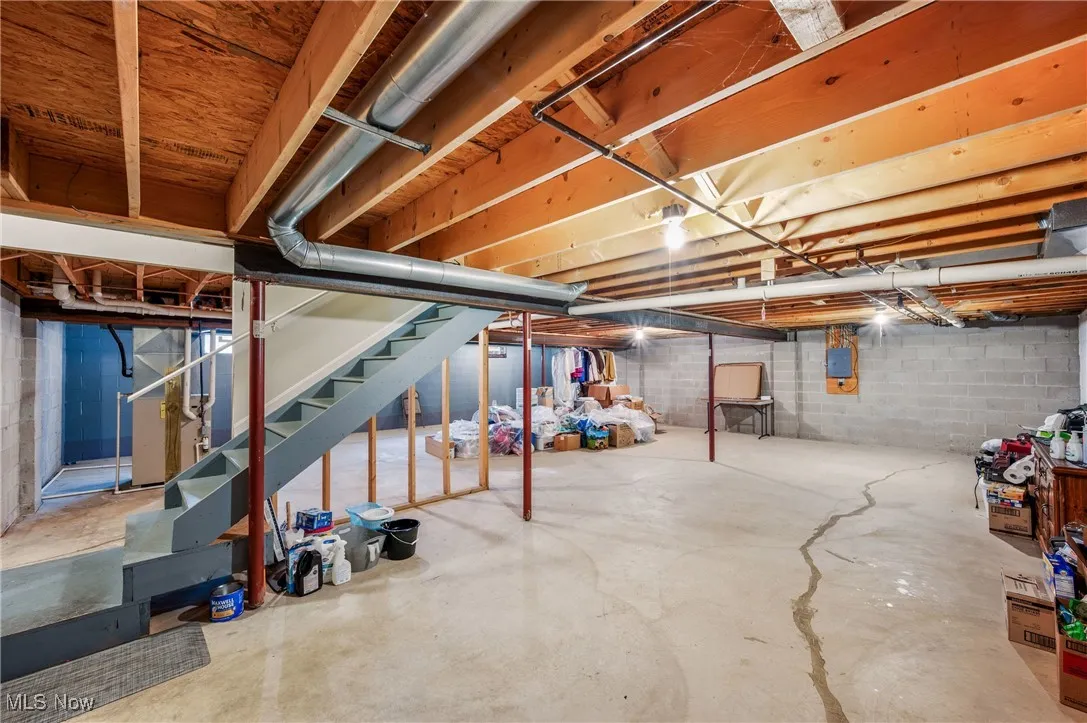 Unfinished below grade area with electric panel and stairway