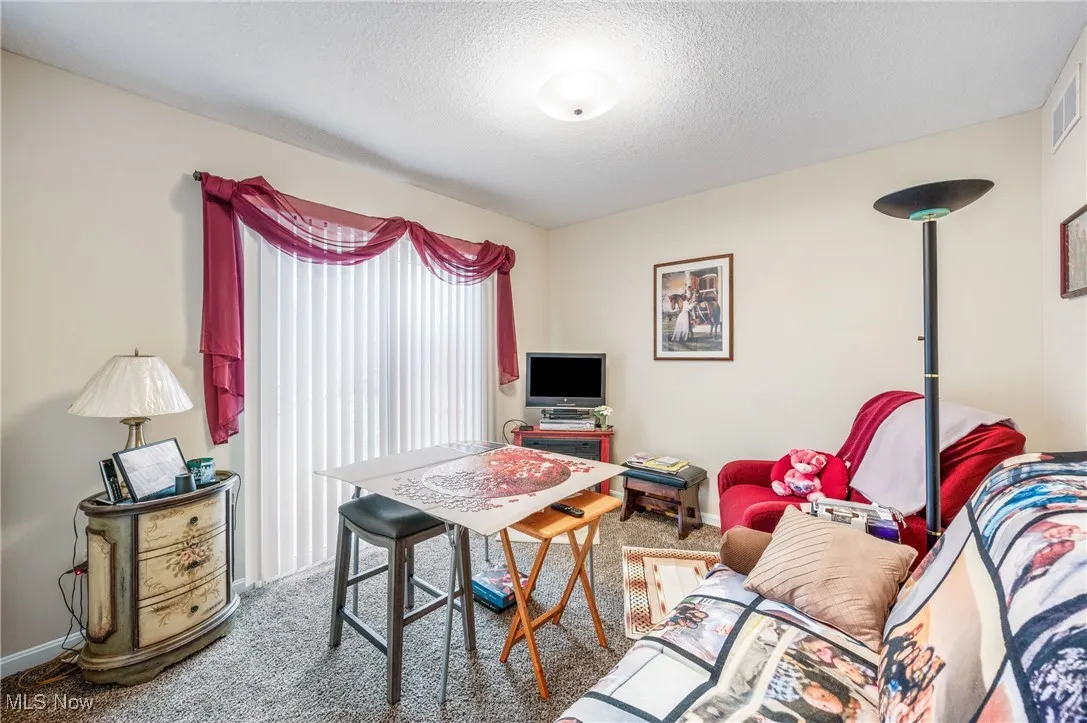 Carpeted living area featuring baseboards, visible vents, and a textured ceiling