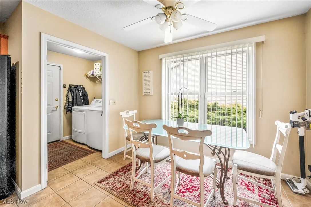 Dining area featuring washer and clothes dryer, baseboards, a textured ceiling, light tile patterned flooring, and a ceiling fan