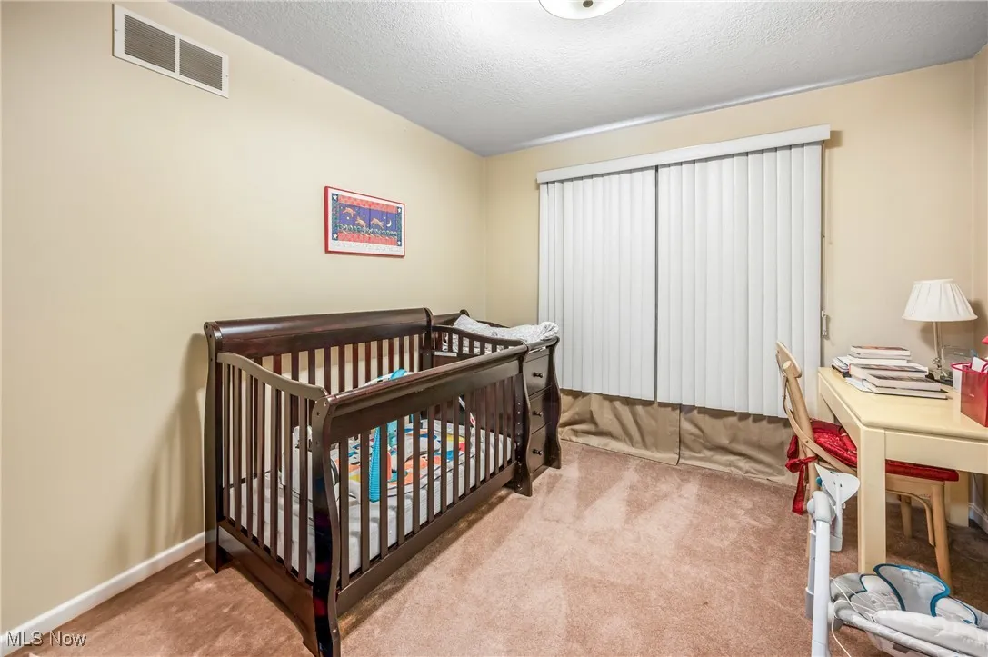 Bedroom with baseboards, a textured ceiling, visible vents, and carpet