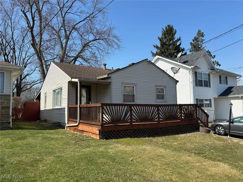 Back of property featuring a lawn and a wooden deck