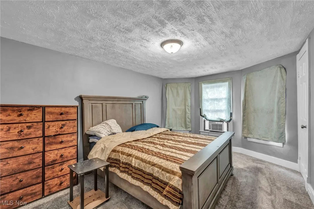 Bedroom with baseboards, carpet floors, and a textured ceiling