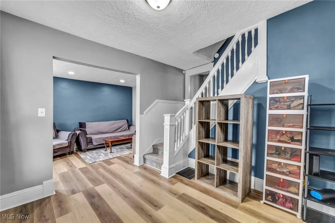 Corridor featuring a wainscoted wall, wood finished floors, stairway, and a textured ceiling
