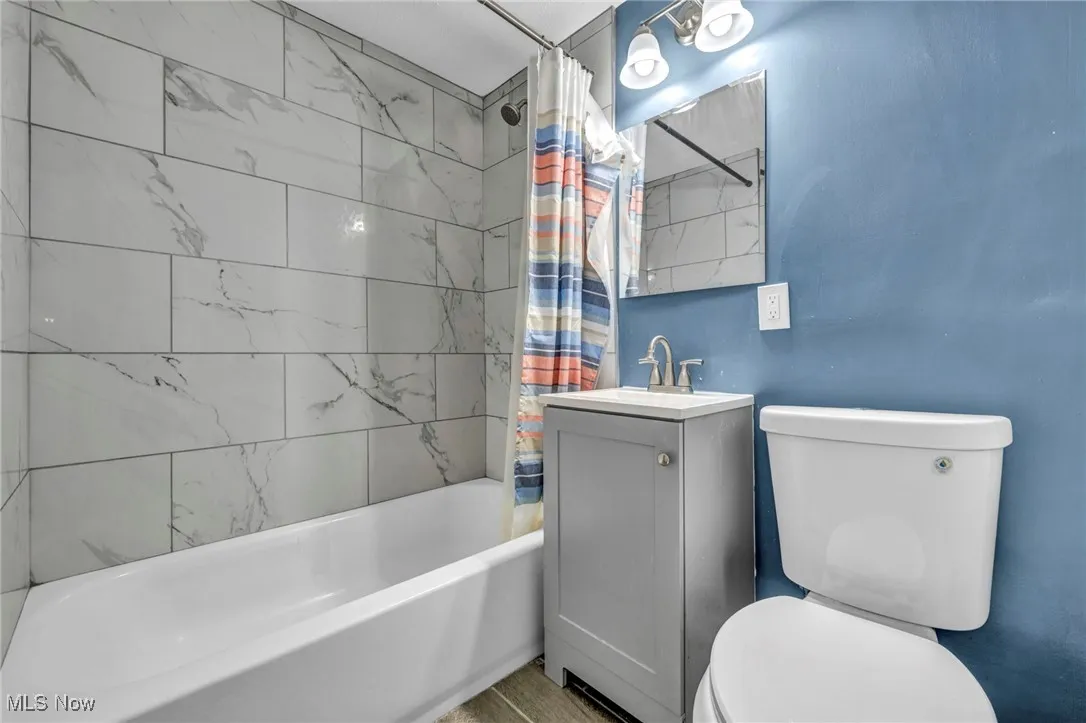 Bathroom featuring toilet, vanity, and shower / bathtub combination with curtain