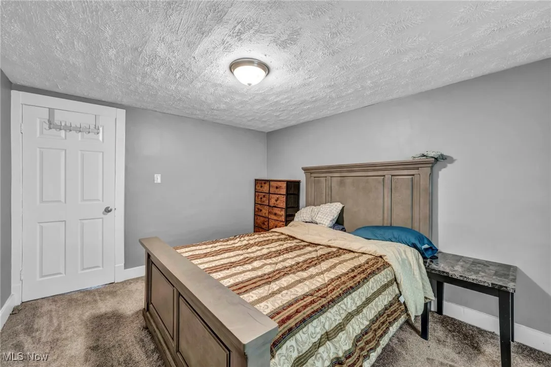 Bedroom with carpet floors, baseboards, and a textured ceiling
