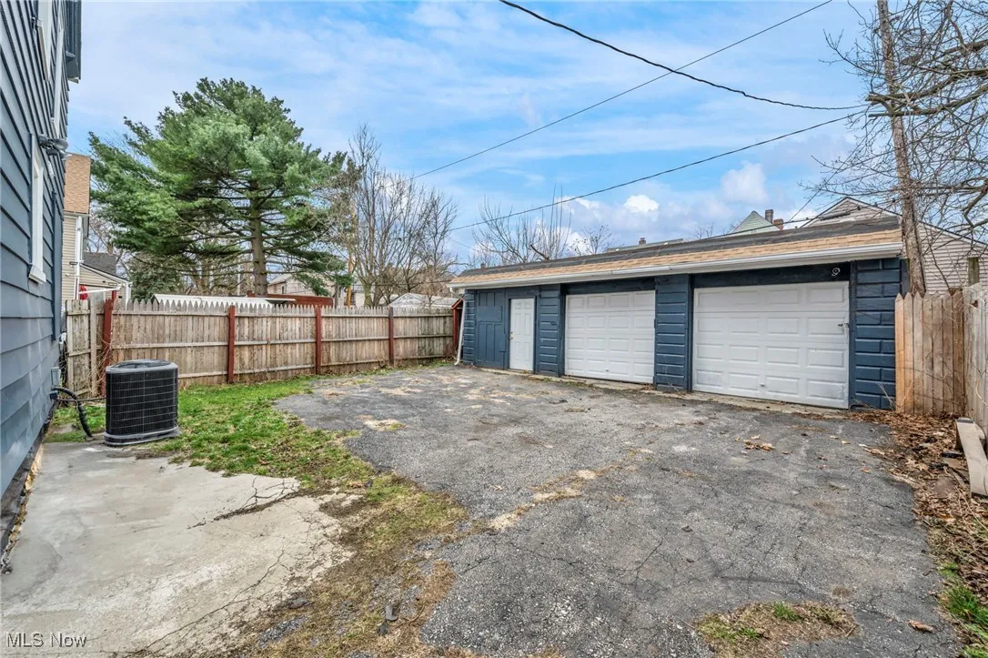 Detached garage featuring fence and cooling unit
