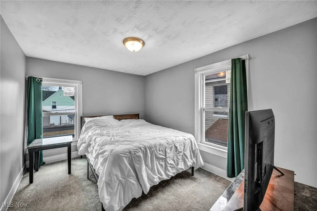 Bedroom featuring baseboards, carpet flooring, and a textured ceiling