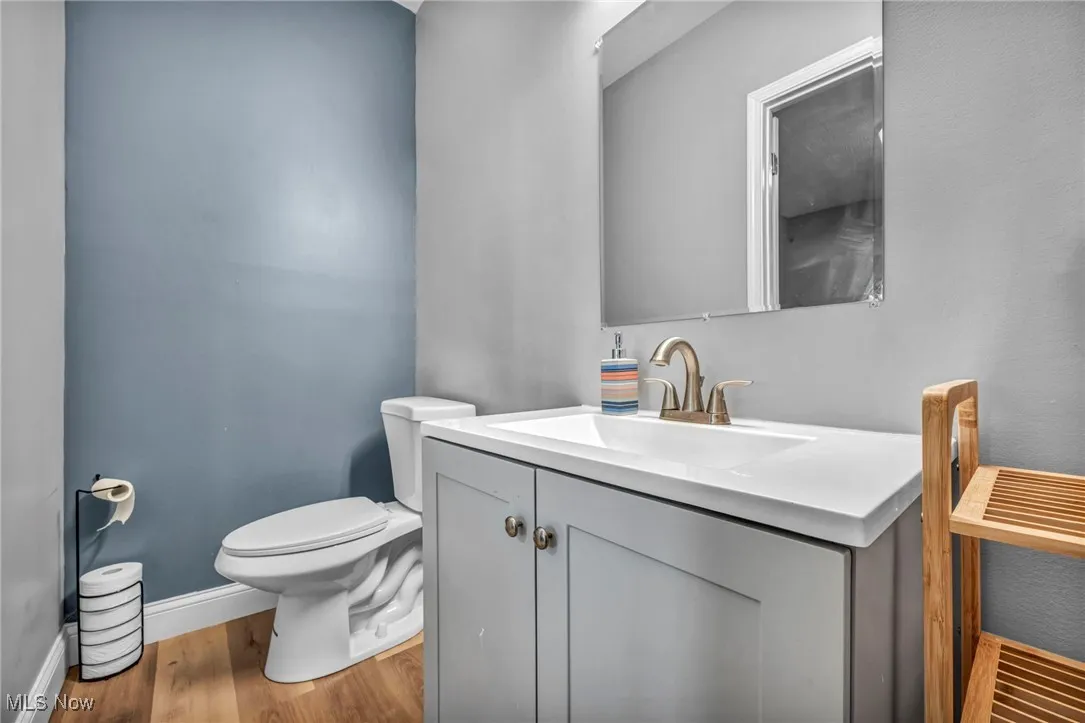 Bathroom featuring baseboards, toilet, vanity, and wood finished floors