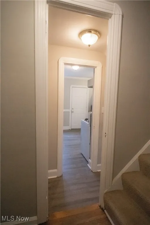 Hall featuring baseboards, dark wood-style flooring, washer / clothes dryer, and stairs