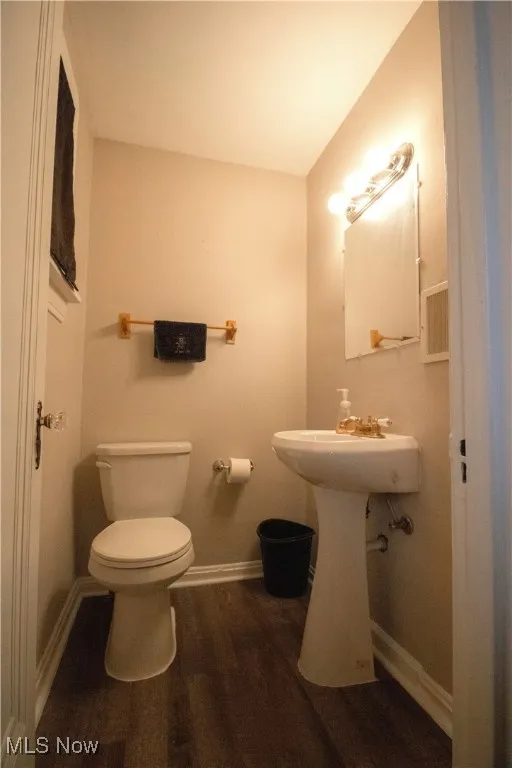 Half Bathroom featuring baseboards, wood finished floors, toilet, and a pedestal sink