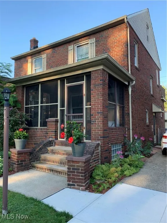 View of front of house with brick siding and a sunroom