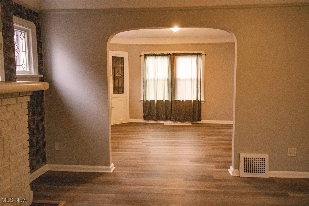 Spare room featuring arched walkways, baseboards, visible vents, and wood finished floors