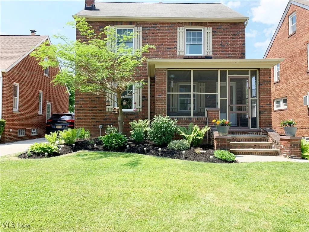 View of front facade featuring a sunroom, brick siding, and a front yard