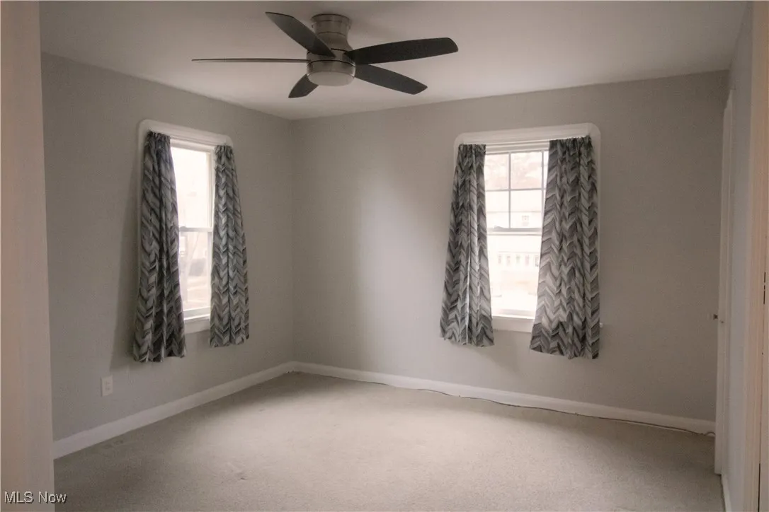 Carpeted bedroom room featuring baseboards, a healthy amount of sunlight, and a ceiling fan