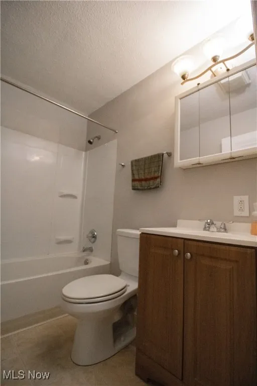 Full bathroom with bathtub / shower combination, toilet, vanity, a textured ceiling, and tile patterned flooring